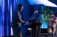 a group of people playing keyboards in front of a stained glass window