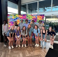 a group of people posing in front of a mural