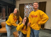 three people in yellow sweatshirts posing for a picture