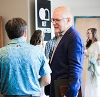 a man in a blue shirt is talking to a man in a blue shirt