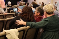 a woman takes a picture of a group of people at a conference