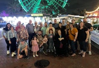 a group of people posing in front of a ferris wheel