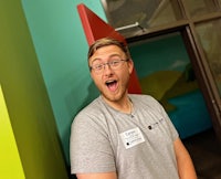 a man in a gray t - shirt standing in front of a colorful door